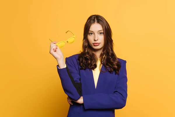 Confident Stylish Girl Holding Yellow Glasses While Looking Camera Isolated — Stock Photo, Image