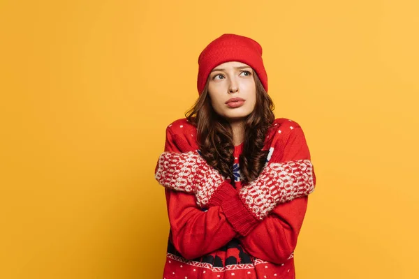 赤い装身具のセーターを着たみすぼらしい女の子黄色で隔離された寒さを感じながら自分自身を抱きしめる — ストック写真