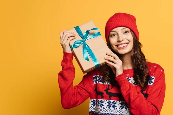Cheerful Girl Hat Red Ornamental Sweater Holding Gift Box Yellow — Stock Photo, Image