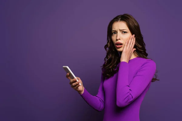 Shocked Girl Touching Face While Holding Smartphone Purple Background — Stock Photo, Image