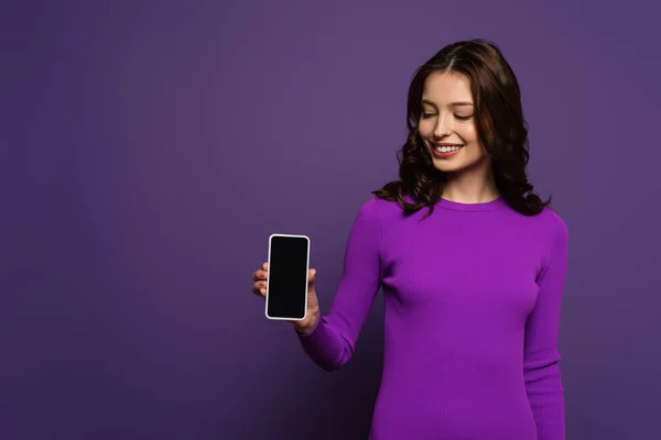 Gülümseyen Kız Mor Arkaplanda Boş Ekranlı Akıllı Telefon Gösteriyor — Stok fotoğraf