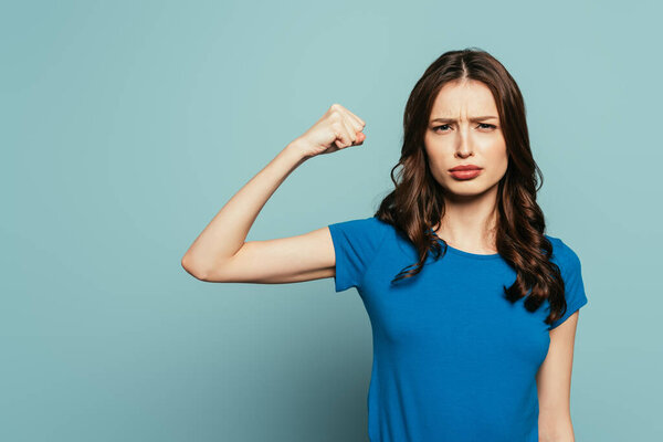 serious girl demonstrating power while looking at camera on blue background
