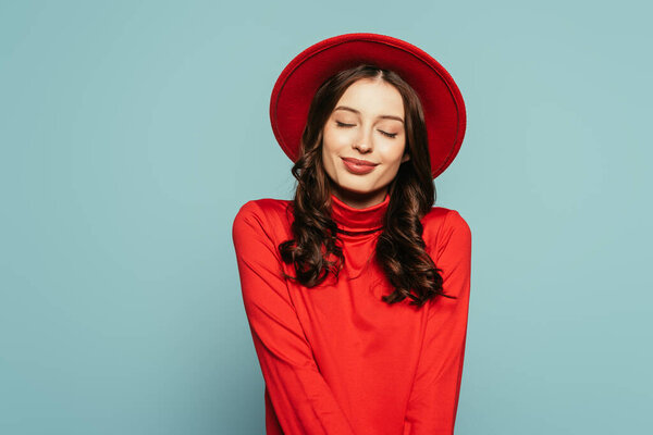 happy, dreamy girl standing with closed eyes isolated on blue