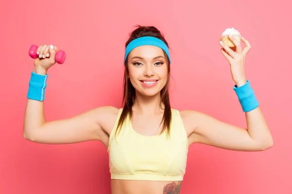 Ung Glad Idrottskvinna Håller Hantel Och Läcker Cupcake Rosa Bakgrund — Stockfoto