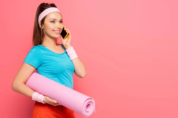 Smiling Sportswoman Holding Fitness Mat While Talking Smartphone Pink Background — Stock Photo, Image