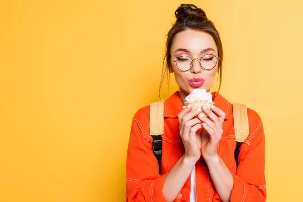 Šťastný Student Zavřenýma Očima Drží Chutný Cupcake Žlutém Pozadí — Stock fotografie