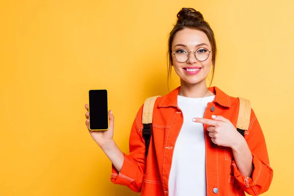 Usmívající Student Ukazuje Prstem Smartphone Prázdnou Obrazovkou Žlutém Pozadí — Stock fotografie