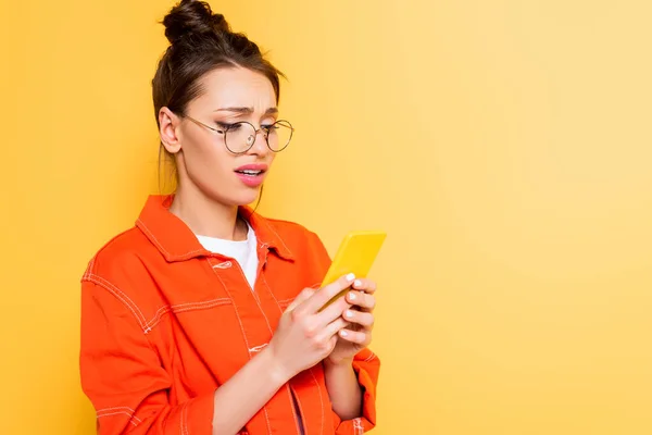 Upset Student Eyeglasses Chatting Smartphone Isolated Yellow — Stock Photo, Image