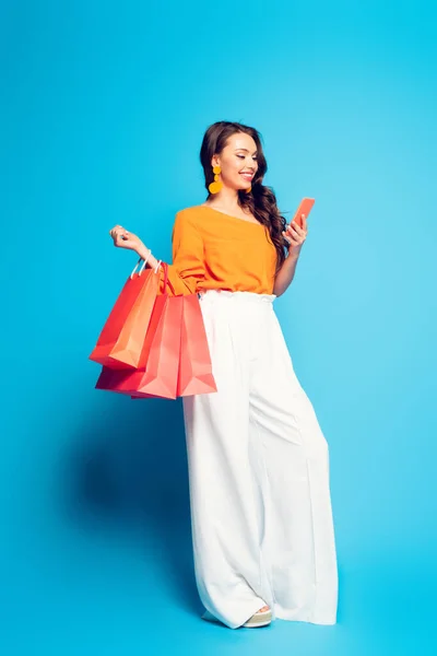 Cheerful Stylish Woman Chatting Smartphone While Holding Shopping Bags Blue — Stock Photo, Image