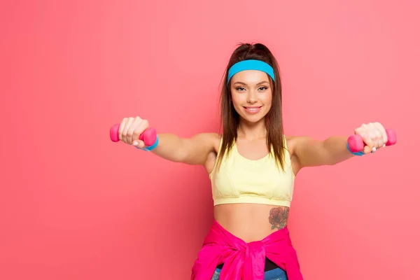 Aantrekkelijke Vrolijke Sportvrouw Training Met Halters Terwijl Glimlachen Camera Roze — Stockfoto
