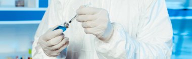 panoramic shot of scientist in latex gloves holding syringe and bottle with vaccine  clipart