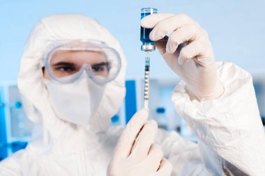Şırınga ve şişeyi aşıyla tutan bilim adamının seçici odağı 