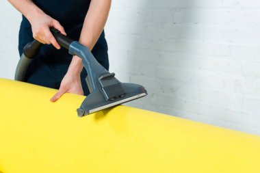 cropped view of cleaner removing dust on sofa with vacuum  clipart