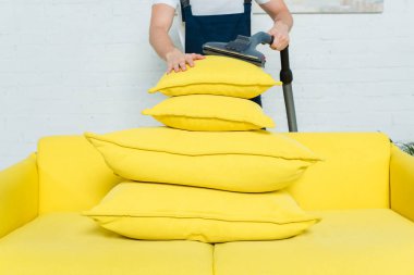 cropped view of cleaner removing dust on stacked pillows with vacuum cleaner  clipart
