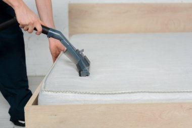 Elektrikli süpürgeyi temizlerken elinde tutan temizleyicinin kırpılmış görüntüsü 