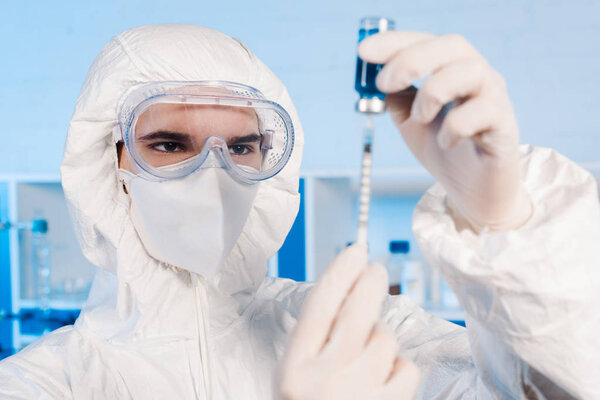 selective focus of scientist in latex gloves holding syringe and bottle with vaccine 