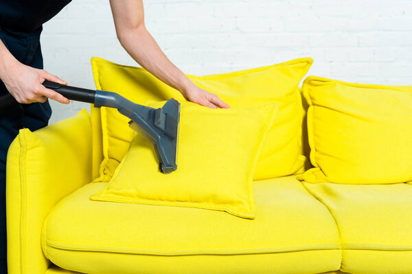 cropped view of cleaner removing dust on pillow with vacuum cleaner 