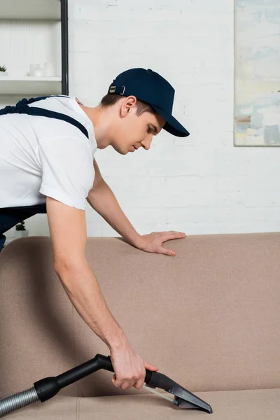 Side View Handsome Cleaner Cap Removing Dust Sofa Vacuum Cleaner — Stock Photo, Image