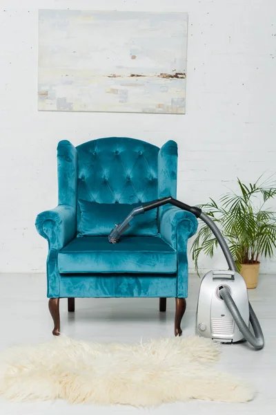 客厅里靠近现代扶手椅的地毯上的真空吸尘器 — 图库照片