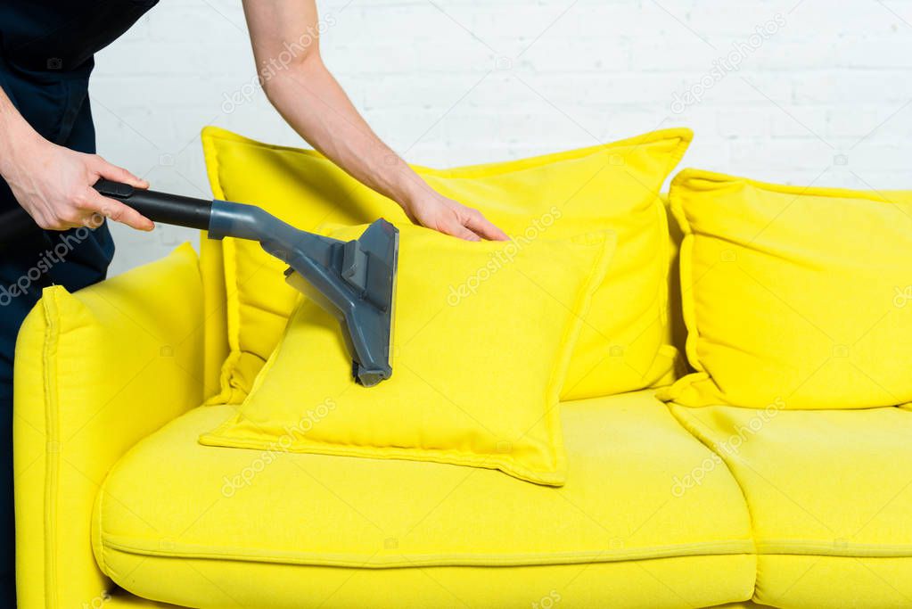 cropped view of cleaner removing dust on pillow with vacuum cleaner 