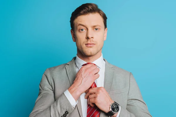 Gutaussehender Selbstbewusster Geschäftsmann Der Krawatte Anfasst Während Isoliert Auf Blau — Stockfoto