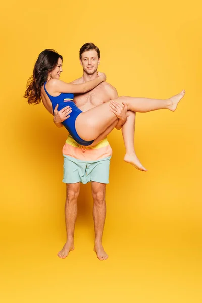 Handsome Shirtless Man Holding Happy Girlfriend Swimsuit Yellow Background — Stock Photo, Image