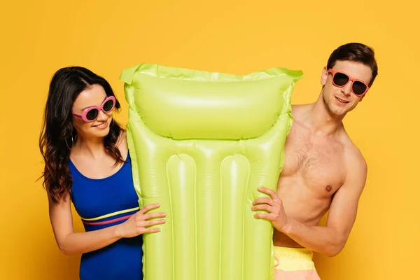 Cheerful Couple Sunglasses Holding Inflatable Mattress Yellow Background — Stock Photo, Image