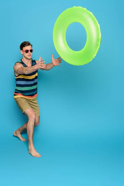 Young Man Striped Singlet Shorts Throwing Inflatable Ring Blue Background — Stock Photo, Image