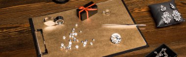Panoramic shot of gemstones, jewelry and gift box on board on wooden table  clipart