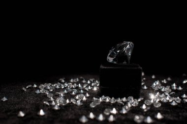 Diamond near gemstones on black velour isolated on black  clipart