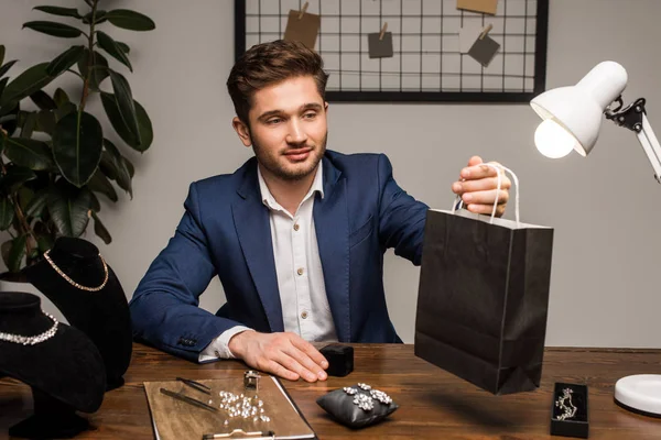 Handsome Jewelry Appraiser Holding Paper Bag Earrings Necklaces Table — Stock Photo, Image