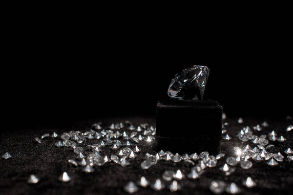 Diamond near gemstones on black velour isolated on black 