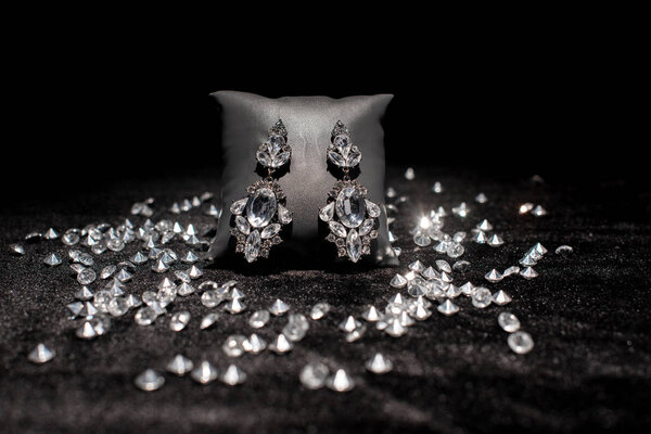 Selective focus of jewelry earnings near gemstones on black velour isolated on black 
