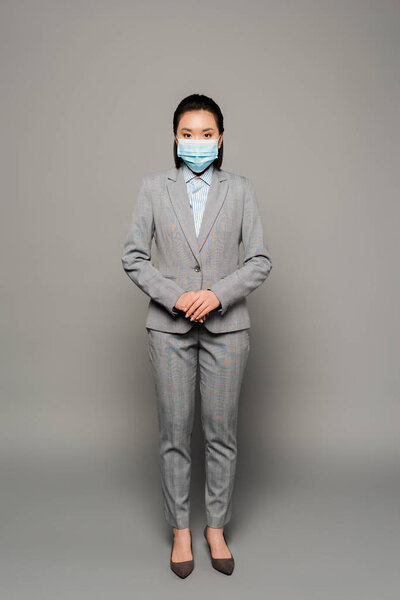 young businesswoman in medical mask on grey background