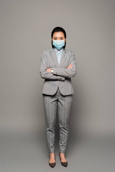 young businesswoman in medical mask on grey background