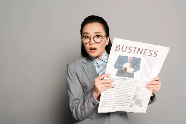 Shocked Young Businesswoman Eyeglasses Holding Business Newspaper Grey Background — Stock Photo, Image
