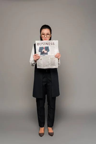 Νεαρή Επιχειρηματίας Γυαλιά Ηλίου Που Διαβάζει Εφημερίδα Γκρι Φόντο — Φωτογραφία Αρχείου