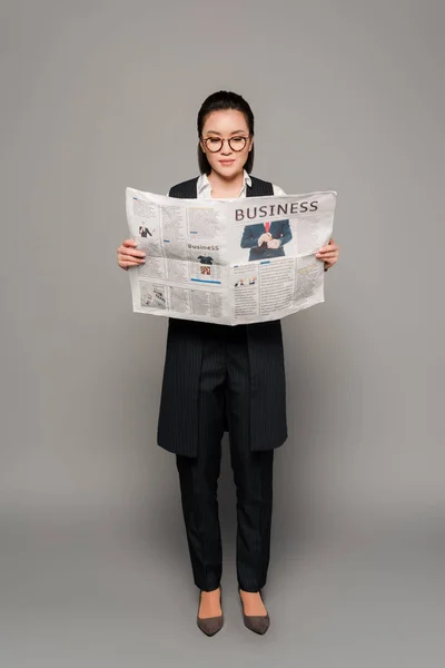 Молода Бізнес Леді Окулярах Читає Газету Сірому Фоні — стокове фото
