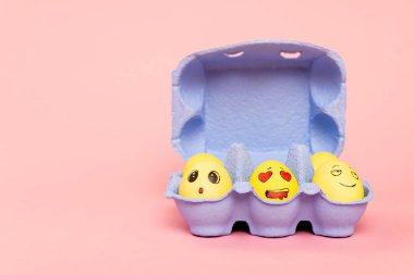 Pembe arka planda mor yumurta tepsisiyle boyanmış tavuk yumurtaları, paskalya konsepti.