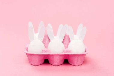 Süslü paskalya tavşanları pembe arka planda yumurta tepsisinde