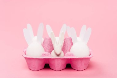 Paskalya tavşanları pembe arka planda yumurta tepsisinde