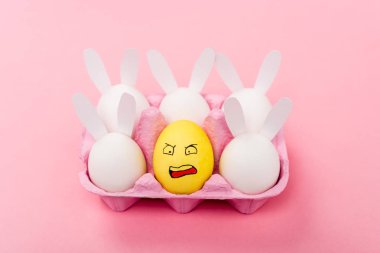 Süslü tavşanlar ve sarı yumurta pembe, paskalya konsepti üzerinde tahriş olmuş yüz ifadesi.
