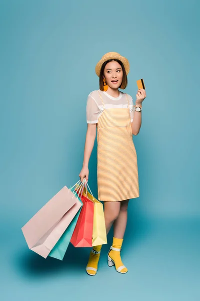 Çizgili Sarı Elbiseli Gülümseyen Asyalı Kız Mavi Arka Planda Alışveriş — Stok fotoğraf