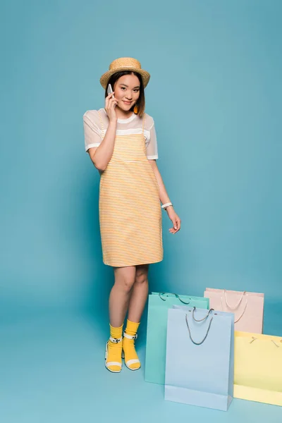 Çizgili Sarı Elbiseli Asyalı Kız Mavi Arka Planda Akıllı Telefondan — Stok fotoğraf