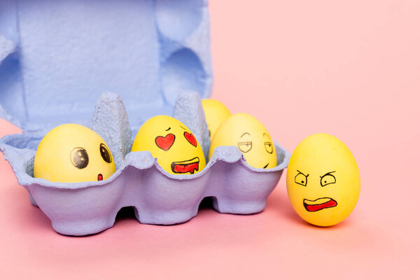 Funny chicken eggs with facial expressions in egg tray on pink, easter concept