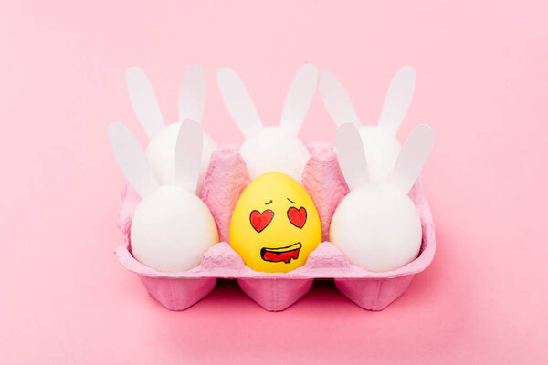 Decorative rabbits and yellow egg with enamored facial expression on pink, easter concept