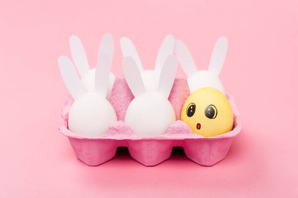 Decorative rabbits and yellow egg with shocked facial expression on pink, easter concept