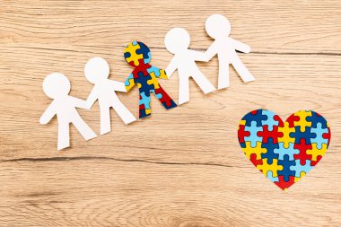 High angle view of special kid with autism among another with decorative heart on wooden background clipart