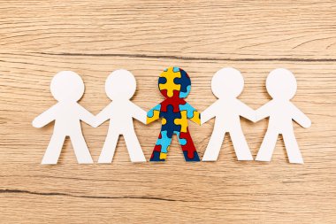 Top view of special kid with autism among another on wooden background clipart