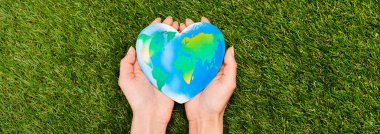 Cropped view of globe in female hands on green, earth day concept clipart